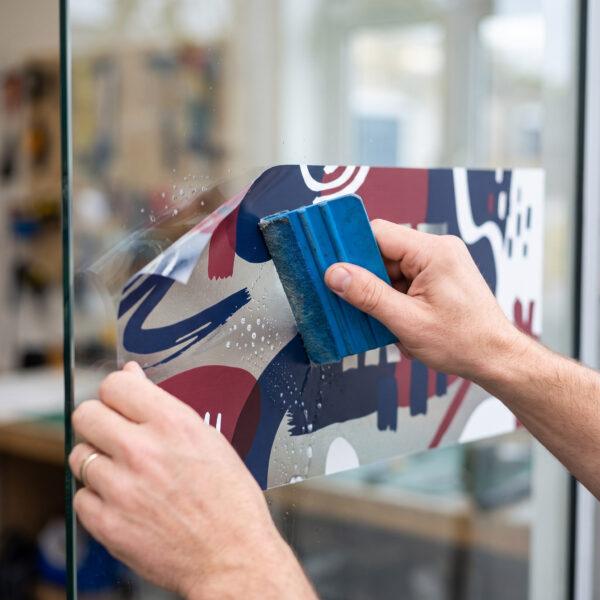 Close-up of a window cling being smoothed onto glass — Sign America Chicago