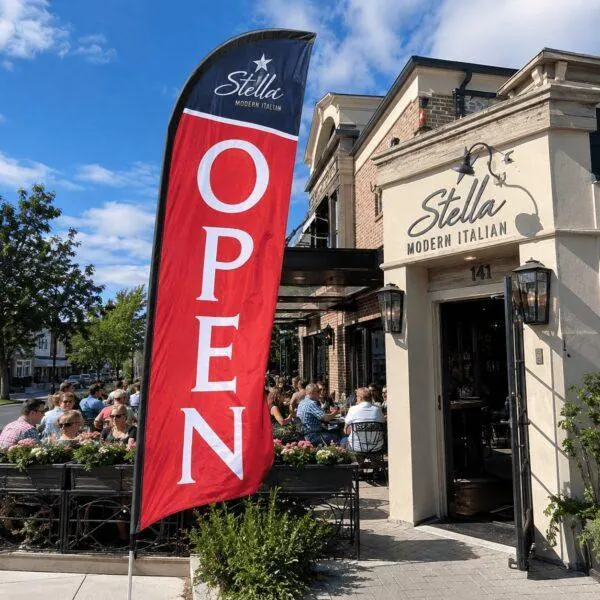 Feather flag flying outside a busy restaurant patio — custom feather flags Sign America Chicago